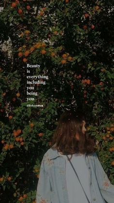 a woman standing in front of a bush with orange flowers and a quote about beauty