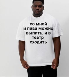 a man standing in front of a white wall wearing a t - shirt with words written on it