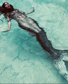 a woman is floating in the water with a mermaid tail and long hair on her head