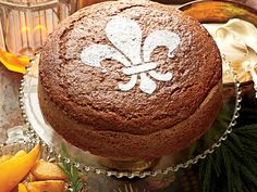 a chocolate cake with a white fleur de lis on it sitting on a platter