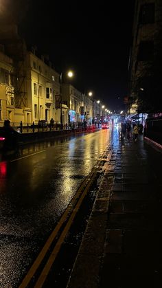 people walking down the street at night in the rain