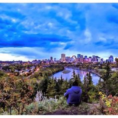 a man sitting on top of a hill overlooking a city