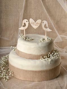 two birds on top of a wedding cake with burlap ribbon and twine