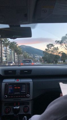 the view from inside a car driving down a road with palm trees in the background