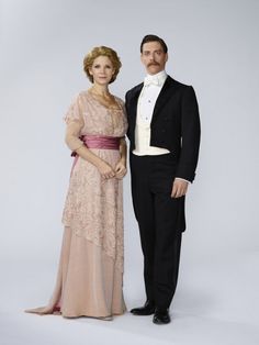 a man and woman dressed in formal wear posing for a photo together on a white background