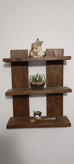 three wooden shelves with two cats sitting on one shelf and a plant in the other