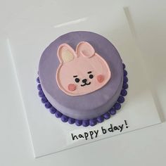 a birthday cake with purple frosting and an image of a bunny on it's face