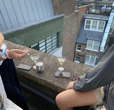 two people are sitting on a ledge and one is holding out her hand to another person