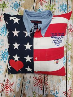 an american flag pillow and shirt on a wooden surface