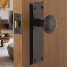 an open door with a black handle and knobs on it's side in a living room