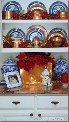 the china cabinet is decorated with blue and white dishes, poinsettis and other decorations