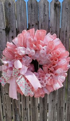 a pink wreath on top of a wooden fence