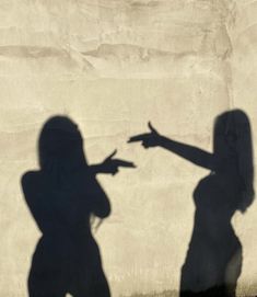 the shadow of two people pointing at each other