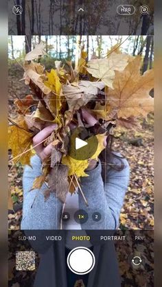 someone taking a photo with their phone of leaves on the ground in front of them