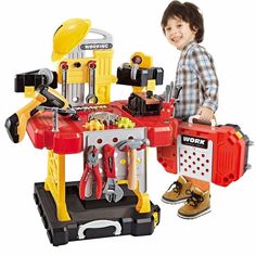 a young boy standing next to a toy workbench with tools on the table