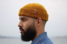 a man with a beard wearing a knitted beanie looking off into the distance