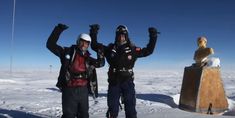 two people standing in the snow with their arms up