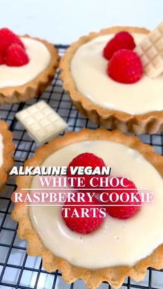 four raspberry cookie tarts on a cooling rack with the words alkadine vegan white choc raspberry cookie tarts