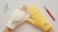 two knitted mittens sitting next to each other on top of a white table