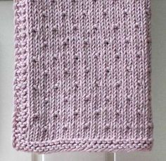 a pink knitted blanket hanging from a hook