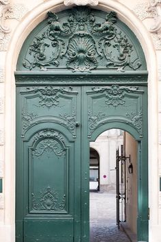 a large green door with ornate carvings on it's sides and an arched doorway