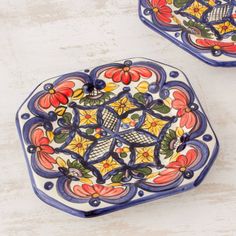 two colorful plates with designs on them sitting on a white counter top next to each other