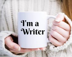 a woman holding a coffee mug with the words i'm a writer on it