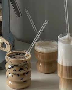 there are three cups with straws in them