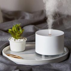 a white humider sitting on top of a bed next to a potted plant