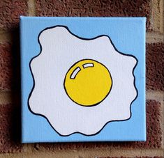 an egg painted on a canvas mounted to a brick wall