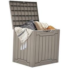 an outdoor storage box with blankets and sweaters in it, on a white background