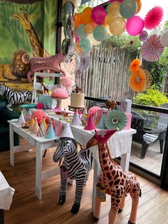 two zebras are standing in front of a table with balloons and decorations on it