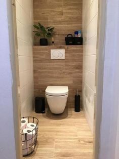 a toilet in a bathroom next to a basket with rolls of toilet paper