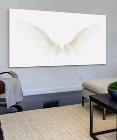 a living room filled with furniture and a large white painting on the wall above it