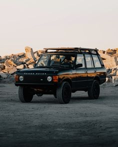 an suv is parked in front of some rocks