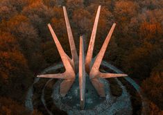 an aerial view of two tall concrete structures in the middle of a forest with trees