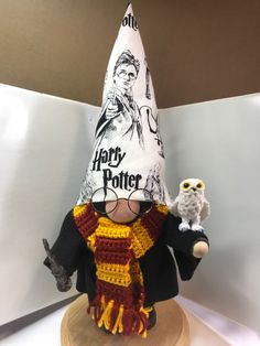 a crocheted harry potter hat and owl figurine on a wooden stand