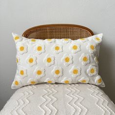 a white and yellow pillow sitting on top of a bed