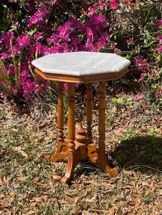 a small table sitting in the grass near some pink flowers and purple flowers behind it