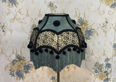 a lamp that is on top of a wooden stand in front of a floral wallpaper