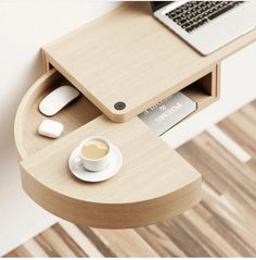 a laptop computer sitting on top of a wooden desk next to a cup of coffee