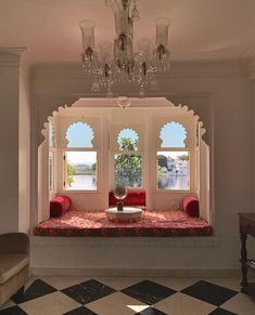 an ornate window seat in the middle of a room with chandelier and windows