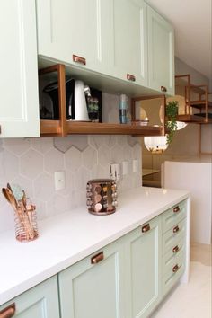 a kitchen with green cabinets and white counter tops