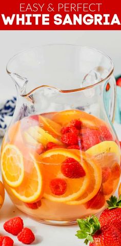 a pitcher filled with oranges and strawberries on top of a table