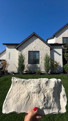 a hand holding a rock in front of a house