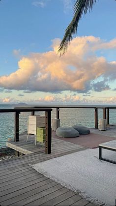 a wooden dock with chairs and palm tree