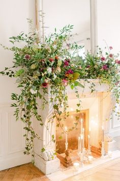 a fireplace decorated with greenery and candles