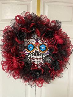 a red and black wreath with a sugar skull on it