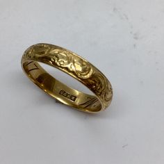 a gold wedding ring on a white surface with the word love engraved in it's center