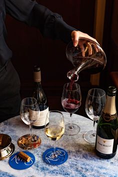 a person pours wine into glasses on a table with plates and utensils